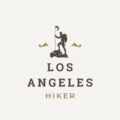 Minimalist logo for LosAngelesHiker.com featuring a silhouette of a hiker with a walking stick on a rocky ground, two small mountain peaks in the background, and the sun or moon overhead. The words 'LOS ANGELES HIKER' are centered below in a bold, clean font, conveying a modern and adventurous spirit.